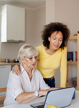 Caregiver and mature woman looking at a laptop