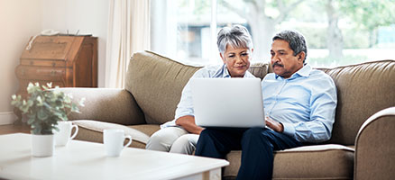 mature man and woman on couch looking at laptop