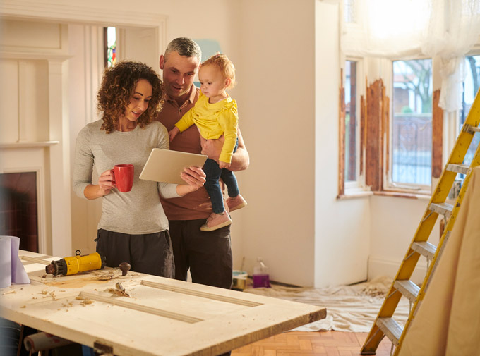 Couple with toddler looking at tablet during home construction.